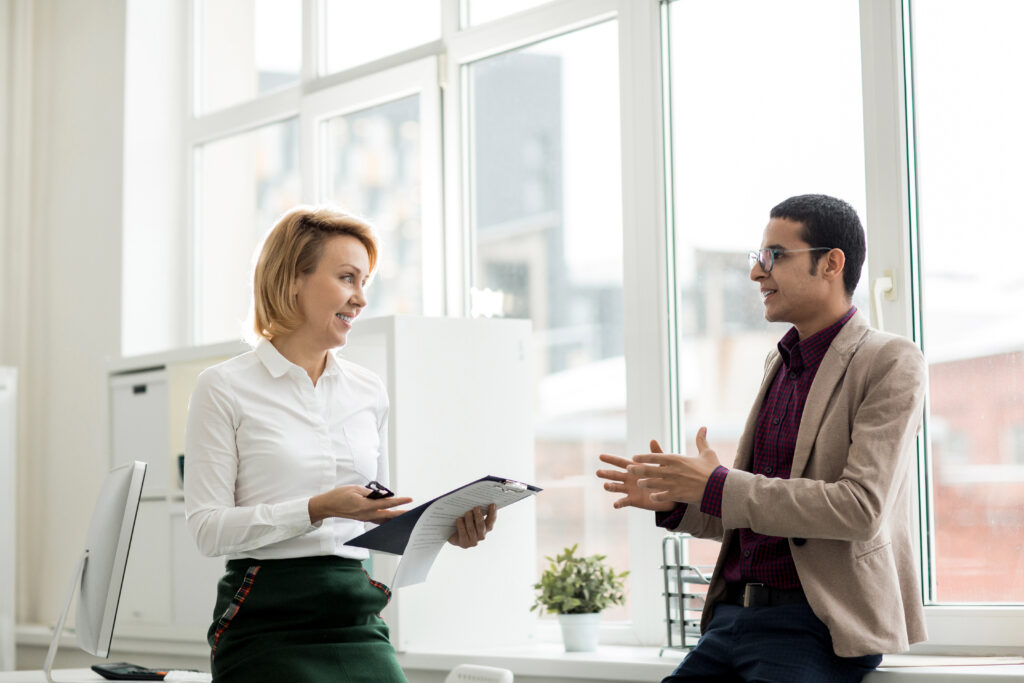 Two contemporary financiers having talk in office and discussing financial papers at meeting